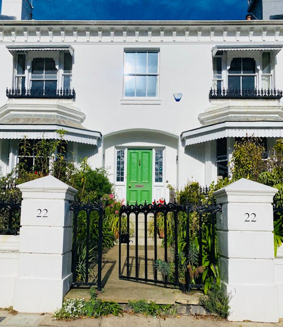 A daytime photograph of a front garden in Forest Gate showcasing neatly trimmed hedges and a well-maintained lawn with vibrant green grass. The garden bed along the pathway contains flowering plants a